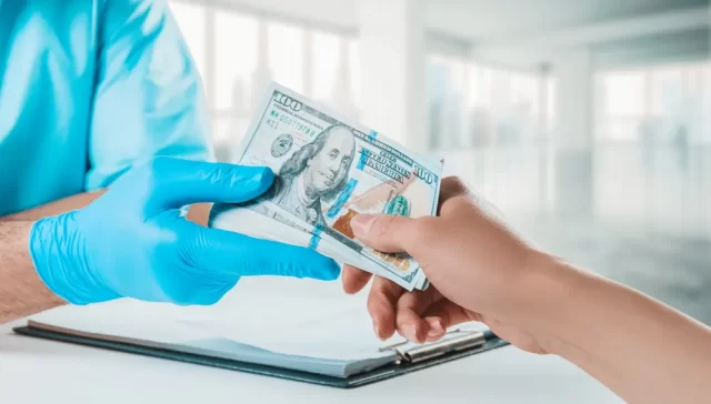 Mulher entrega dinheiro para médico com luvas