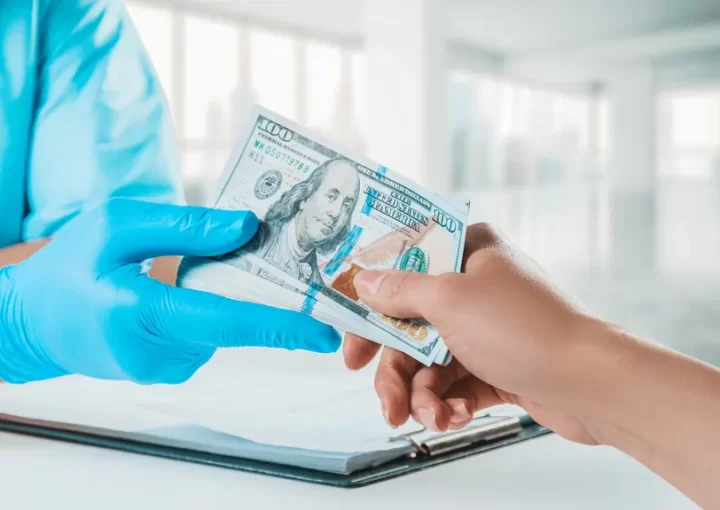 Mulher entrega dinheiro para médico com luvas